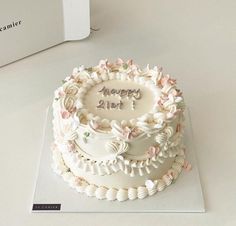 a white cake with flowers on it sitting on top of a table next to a box