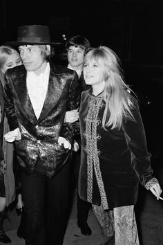 black and white photograph of three people dressed up in disco outfits, one wearing a top hat