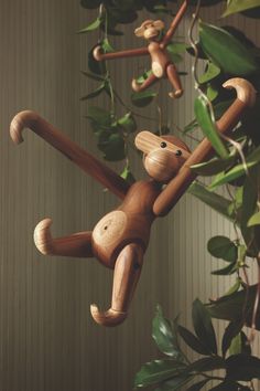 two wooden monkey figurines hanging from a plant