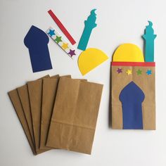 paper cutouts and crafting supplies laid out on a white surface, including a bag with the shape of a mosque