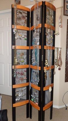 a jewelry cabinet with lots of necklaces hanging from it's sides in a living room