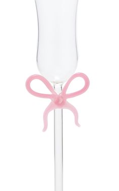 a wine glass with a pink bow on the top and bottom, sitting in front of a white background