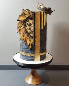 a black and gold cake with a lion on it's side sitting on a pedestal