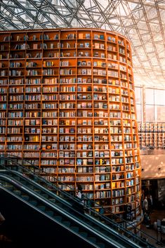 the inside of a library with many bookshelves on each side and an escalator to the second floor