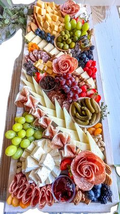 an assortment of cheeses, fruits and meats on a platter