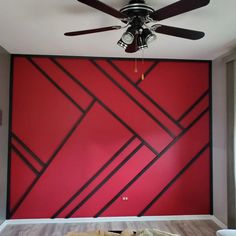 a ceiling fan in front of a red wall with black and white lines on it