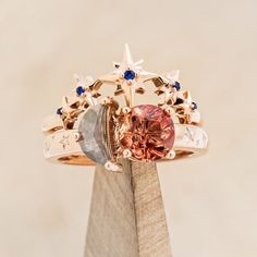 a ring with two different colored stones on top of it, sitting on a piece of wood