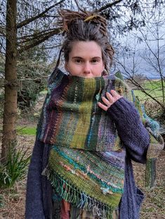 a woman with dreadlocks wearing a multicolored shawl in the woods