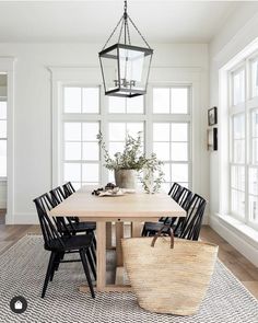 a dining room table with black chairs and a basket on the floor next to it