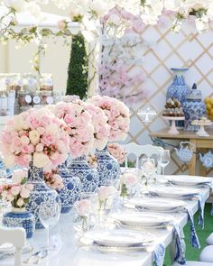 a table set up with flowers and plates for an outdoor wedding reception at the beach