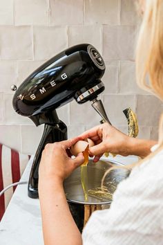 a woman is using an electric blender to make something