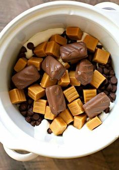 a white bowl filled with chocolate and peanut butter pieces on top of a wooden table