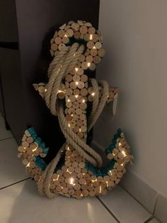 an anchor made out of wine corks with lights on it's sides and rope wrapped around the ends