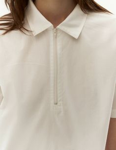 Introducing our timeless white polo shirt, a versatile and stylish addition to your wardrobe. This classic piece features a polo collar and a front zip fastening, offering a touch of sophistication to design. Create a variety of chic ensembles by pairing it with our faux-leather skirt for an edgy and fashion-forward look or with shorts for a casual and contemporary style. dusty pink color polo collar front zip fastening short sleeves straight ham White Collared Tops For Everyday, Modern White Tops With Collared Neckline, Classic Cotton Half-zip Top, White Collared Neckline Tops For Everyday, Dusty Pink Color, T Shirts White, White Polo Shirt, White Polo, Polo T Shirts