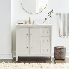 a white bathroom with a round mirror above the sink and rug on the floor next to it