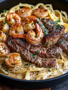 steak and shrimp with pasta in a black bowl on a wooden table, ready to be eaten