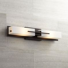 two light bathroom fixture mounted on the side of a wall in a room with tile flooring