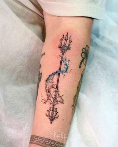 a tattoo on the arm of a person with an arrow and watercolor paint splattered on it