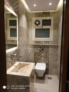 a bathroom with a toilet, sink and mirror on the wall next to each other