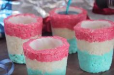 four cupcakes with pink, blue and white frosting in them on a table