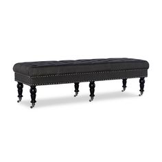 an upholstered bench with black legs and nail polishing on the top, in front of a white background