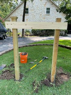 a bucket and tools are sitting on the grass in front of a wooden structure that is being built