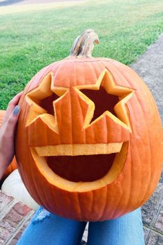 a person holding up a carved pumpkin in front of their face