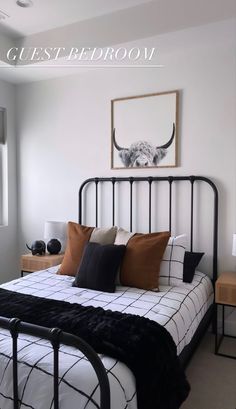 a black and white bed in a bedroom next to a window with an animal painting on the wall