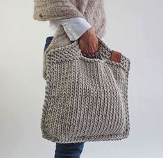 a person holding a knitted bag in their hand and the bottom half of it