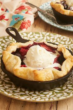 a strawberry pie with ice cream on top in a cast iron skillet sitting on a wooden table