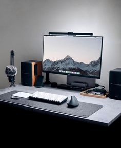 a computer monitor sitting on top of a desk next to speakers and a keyboard in front of it