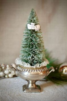 a small christmas tree sitting on top of a silver bowl