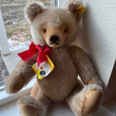 a brown teddy bear sitting on top of a window sill