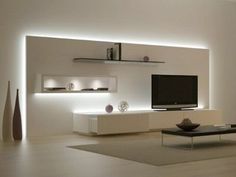 a modern living room with white walls and lighting on the wall, furniture in front of tv