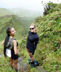 two young women standing on the side of a mountain