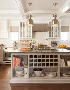 a kitchen with white cabinets and lots of plates on the counter top in front of an island