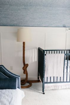 a baby crib next to a lamp in a room with white carpet and blue walls