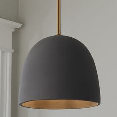 a black and gold pendant light hanging from the ceiling in a room with white walls