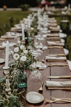 a long table is set up with white flowers and candles for an outdoor wedding reception