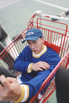 a man sitting in a shopping cart with his hand on the ground next to him