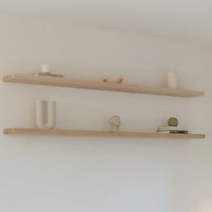 two wooden shelves with white vases on them