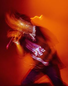 a blurry image of a man with a guitar in his hand and an orange background