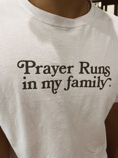 a woman wearing a white shirt with the words prayer runs in my family on it