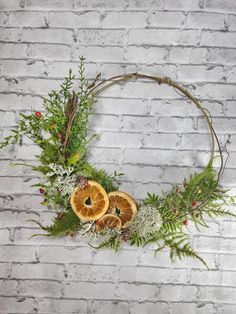 a wreath with orange slices and greenery on a white brick wall in the background