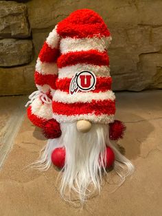 a red and white knitted gnome hat with the letter u on it's side