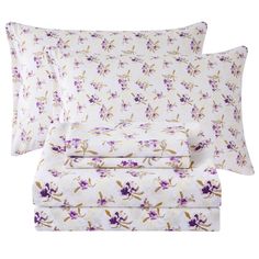 three pillows and two pillow cases with purple flowers on white sheets, one is folded in half