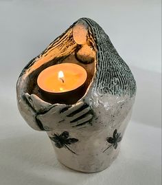 a small candle holder with a fingerprint design and a lit candle in the middle