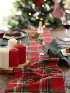 the table is set for christmas dinner with red and white candles in front of it