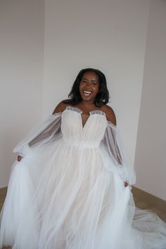 a woman in a white dress standing on a bed with her arms around her waist