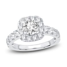 a white gold ring with diamonds on the sides and a halo setting in the center